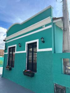 un edificio verde con due finestre e fiori sopra di Casa Maria Mar a São José