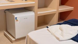 um quarto com uma geladeira branca ao lado de uma escrivaninha em Oasis do Mar Hotel - A melhor vista de Itapema em Itapema