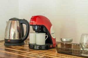 Coração da Terra Praia do Rosa في برايا دو روزا: آلة صنع قهوة حمراء وأكواب على طاولة خشبية