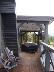 bañera de hidromasaje en una terraza con 2 sillas en Black Crest, en Vyshkiv