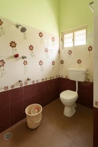 Bhakti Bliss Homestay - Spacious 2bhk AC Apartment near Padmavati Ammavari Temple in Tirupati في تيروباتي: حمام به مرحاض وزهور على الحائط