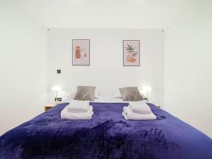 ein großes lila Bett mit zwei Kissen darauf in der Unterkunft Suite Feel Good - Appartement in Argenteuil