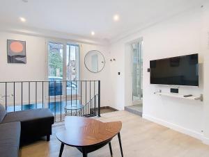 ein Wohnzimmer mit einem Sofa und einem Fernseher an der Wand in der Unterkunft Suite Feel Good - Appartement in Argenteuil
