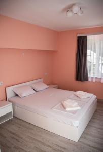 a bedroom with a large white bed with orange walls at Dzhorgovata Guesthouse in Govedartsi
