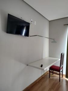 Pousada Pérola Mineira في بيوي: غرفة مع تلفزيون على جدار مع كرسي