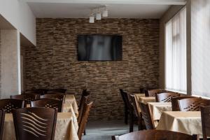 a dining room with tables and a tv on a brick wall at Dzhorgovata Guesthouse in Govedartsi