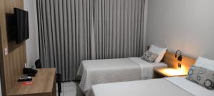 Una habitación de hotel con dos camas y un televisor. en Abudi Hotel, en Cuiabá