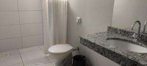 a bathroom with a toilet and a sink and a shower at Abudi Hotel in Cuiabá