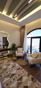 Una sala de estar con muebles blancos y una gran ventana. en Nasma chalets, en Barka