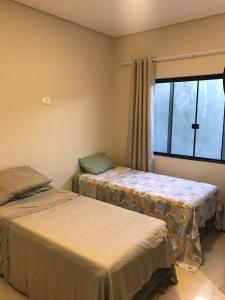 duas camas em um quarto com janela em Linda casa com piscina - locação temporada em itapoá sc em Itapoa