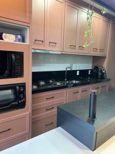 a kitchen with brown cabinets and a black counter top at Apartamento Alto Padrão in Porto Belo +2 photos