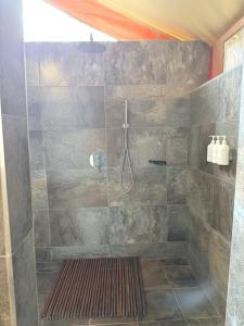 La salle de bains est pourvue d'une douche et d'un grand mur en pierre. dans l'établissement Burko Luxury Camp & Lodge, à Arusha 4 autres photos
