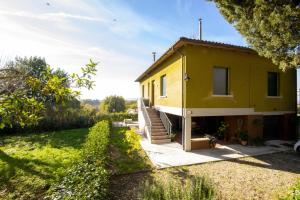 una casa gialla con una scala in un cortile di In Mons Iunonis ad Arezzo