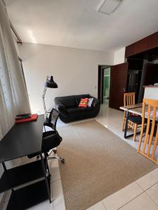 Una sala de estar con un sofá negro y una mesa. en Apartamento completo com Serviço de Quarto em Alphaville, en Barueri