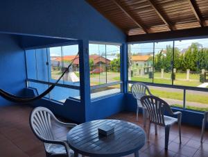 a room with a table and chairs and windows at Casa paulo e nubia in Imbé