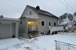 ein Haus mit einem schneebedeckten Hof davor in der Unterkunft Coastal Comfort Ure in Vestvågøya