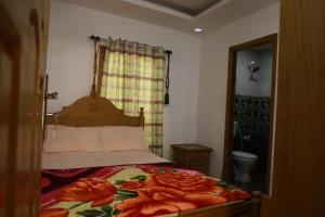 a bedroom with a bed with a floral bedspread at Munnar Stays - Homestay & Resort in Devikolam