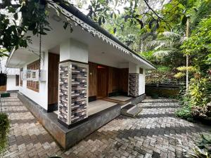 a small white house with a porch and a courtyard at Munnar Stays - Homestay & Resort in Devikolam