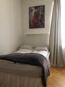 a bed in a bedroom with a painting on the wall at Green House Apartment in Kaunas