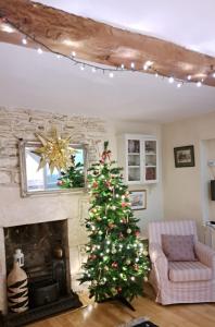 a christmas tree in a living room with a fireplace at Half-pint Cottage in Stroud