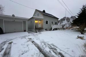 ein Haus mit einem schneebedeckten Hof davor in der Unterkunft Coastal Comfort Ure in Vestvågøya