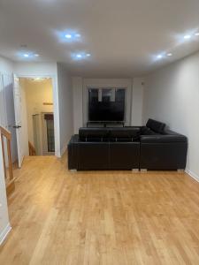 Charming Family Home in Peaceful Laval في لافال: غرفة معيشة مع أريكة سوداء وتلفزيون بشاشة مسطحة