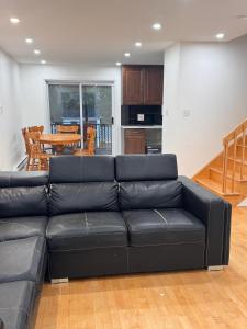 Charming Family Home in Peaceful Laval في لافال: أريكة جلدية سوداء في غرفة معيشة مع طاولة