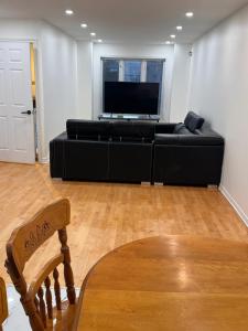 Charming Family Home in Peaceful Laval في لافال: غرفة معيشة مع أريكة سوداء وتلفزيون