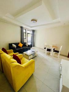 un salon avec un canapé jaune et une table dans l'établissement Iwabo Apartments Kigali Airport Kanombe, à Kigali