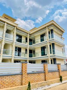un grand bâtiment avec une clôture en briques devant lui dans l'établissement Iwabo Apartments Kigali Airport Kanombe, à Kigali