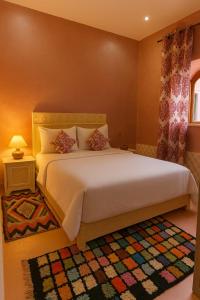 a bedroom with a large white bed and a rug at Grotte Salwa in Aït Benhaddou