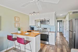 216A Sea Cabin في جزيرة النخيل: مطبخ مع دواليب بيضاء وطاولة مع كراسي حمراء