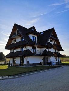 GÓRALSKIE NOWE APARTAMENTY BIAŁKA - Skibus, Sauny, Bania, Sale zabaw - w cenie في بيالكا تاترزانسكا: مبنى عليه سقف اسود