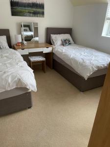 a bedroom with two beds and a desk and a mirror at Swn yr Coed in Sennybridge