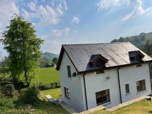 a white house with a shingled roof at Swn yr Coed in Sennybridge