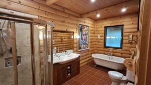 une salle de bain avec deux lavabos et une baignoire et des toilettes dans l'établissement Eaglewood Lodge, à Carrowkennedy 18 autres photos