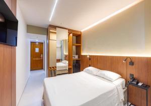 a bedroom with a white bed and a television at Majestic Rio Palace Hotel in Rio de Janeiro +26 photos