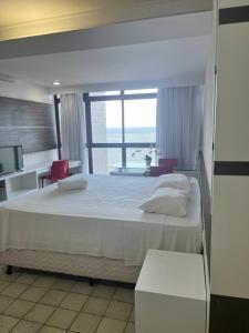 une chambre avec un grand lit avec une grande fenêtre dans l'établissement Suíte Golden Beach Frente Mar, à Récife 32 autres photos