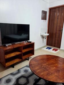 a living room with a table and a large television at Serene63 Studios Kenol,Muranga in Gitura