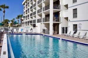 Cape Winds 204 في كيب كانافيرال: مسبح امام مبنى فيه كراسي