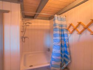 a bathroom with a tub and a shower curtain at Gemütliches Ferienhaus im skandinavischen Stil in Granzow +16 photos