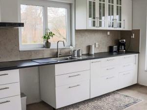 5 star holiday home in FALKENBERG في Anderstorp: مطبخ بخزائن بيضاء ومغسلة ونافذة