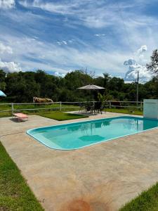a swimming pool with a table and an umbrella at Chácara Segredo in Bonito