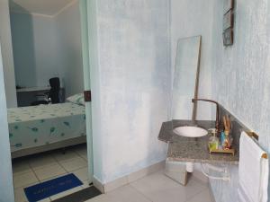 a bathroom with a sink and a bed at suite confortavel temporada caraguatatuba in Caraguatatuba