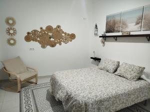 a bedroom with a bed and a chair at Habitaciones Andaluzas in Ronda