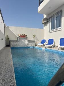 een zwembad met blauwe stoelen naast een gebouw bij Villa Pure Luxor in Luxor