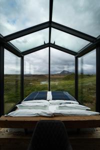Panorama Glass Lodge SOUTH في هيلاّ: سرير في غرفة ذات نافذة كبيرة