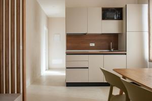 a kitchen with white cabinets and a wooden table at Marina Suite Elba in Marina di Campo