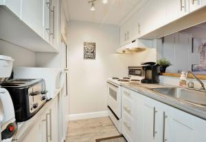 a white kitchen with a sink and a stove at Hameau 28-41 studio in Stoneham