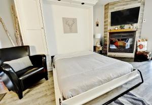 a bedroom with a bed and a chair and a television at Hameau 28-41 studio in Stoneham